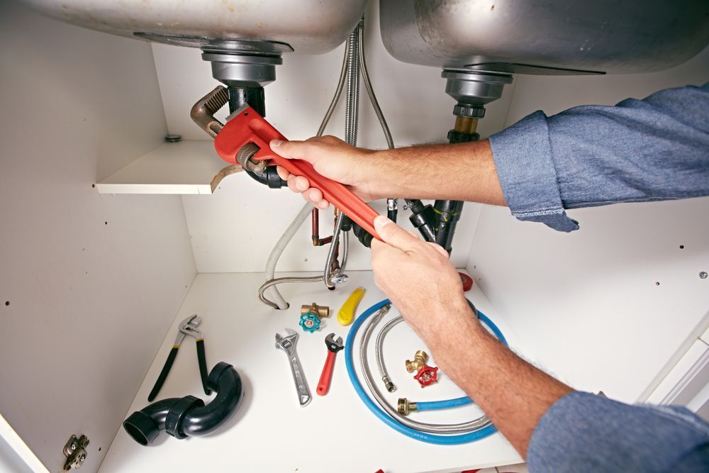 A Plumber Is Fixing A Sink With A Wrench — CG Plumbing & Drainage In Branxton, NSW