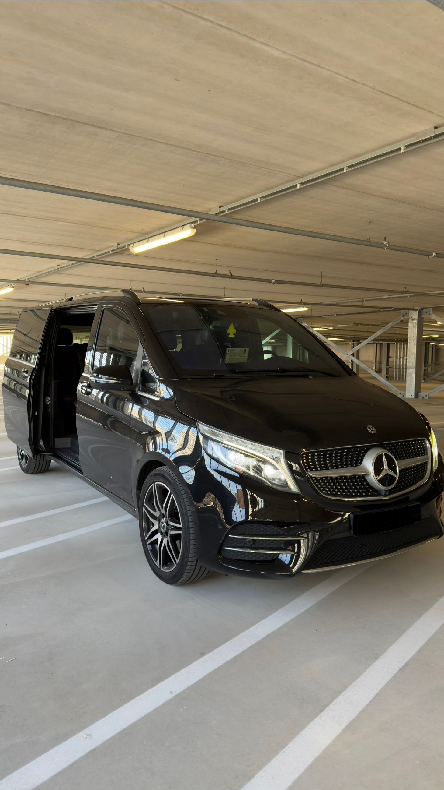 The interior of a black luxury car with quilted leather seats, ambient lighting, and a view of the dashboard.