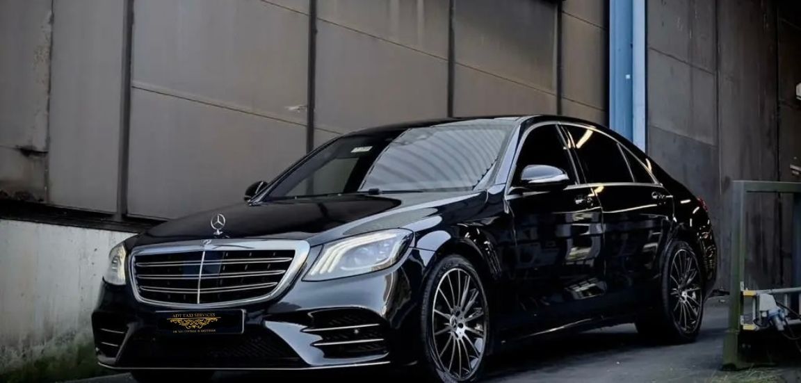 A black mercedes benz s class is parked in front of a building.