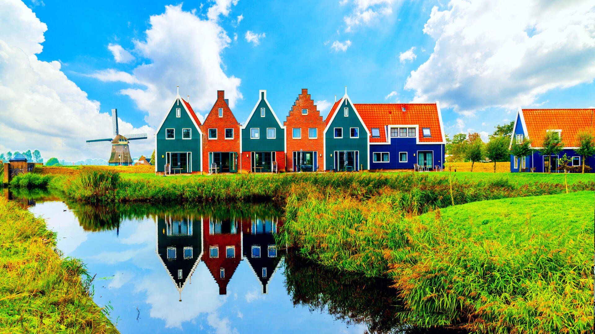 A row of colorful houses are lined up next to a body of water.