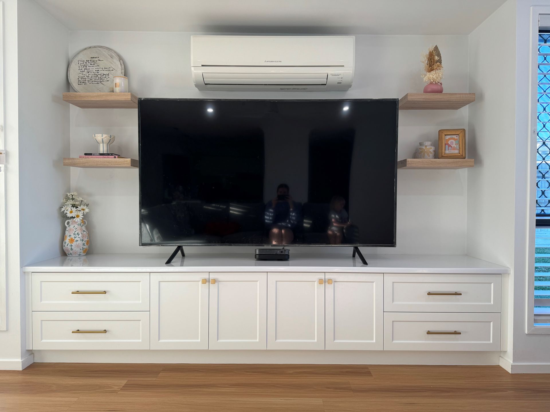 White built-in TV wall with flat-screen, shelves, and drawers in a bright living room — Valley Cabinetmakers In Biloela, QLD 