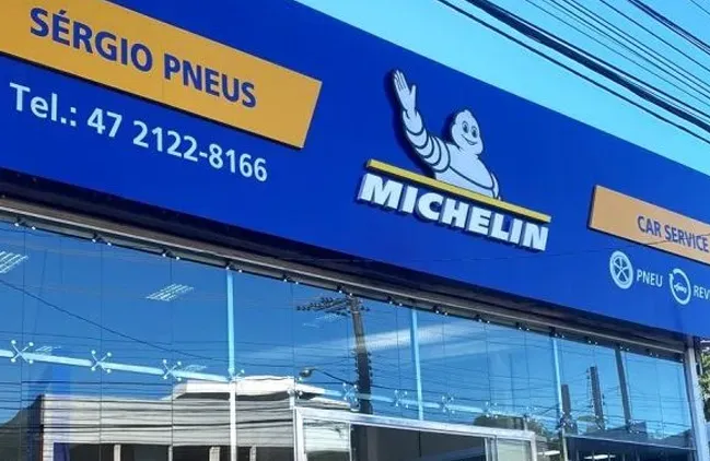Fachada da loja de pneus Sérgio Pneus com placa azul da Michelin e fachada de vidro.