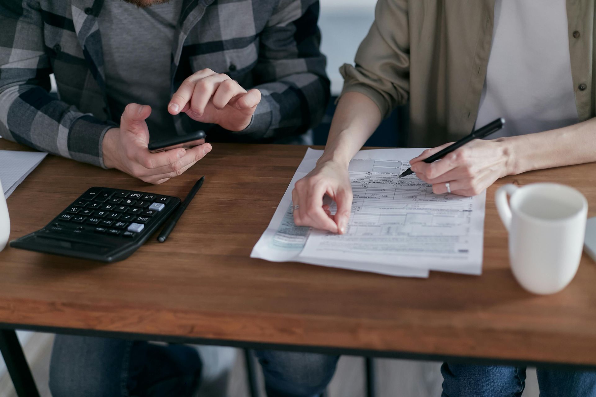 A woman is sitting at a desk with a laptop and a calculator.