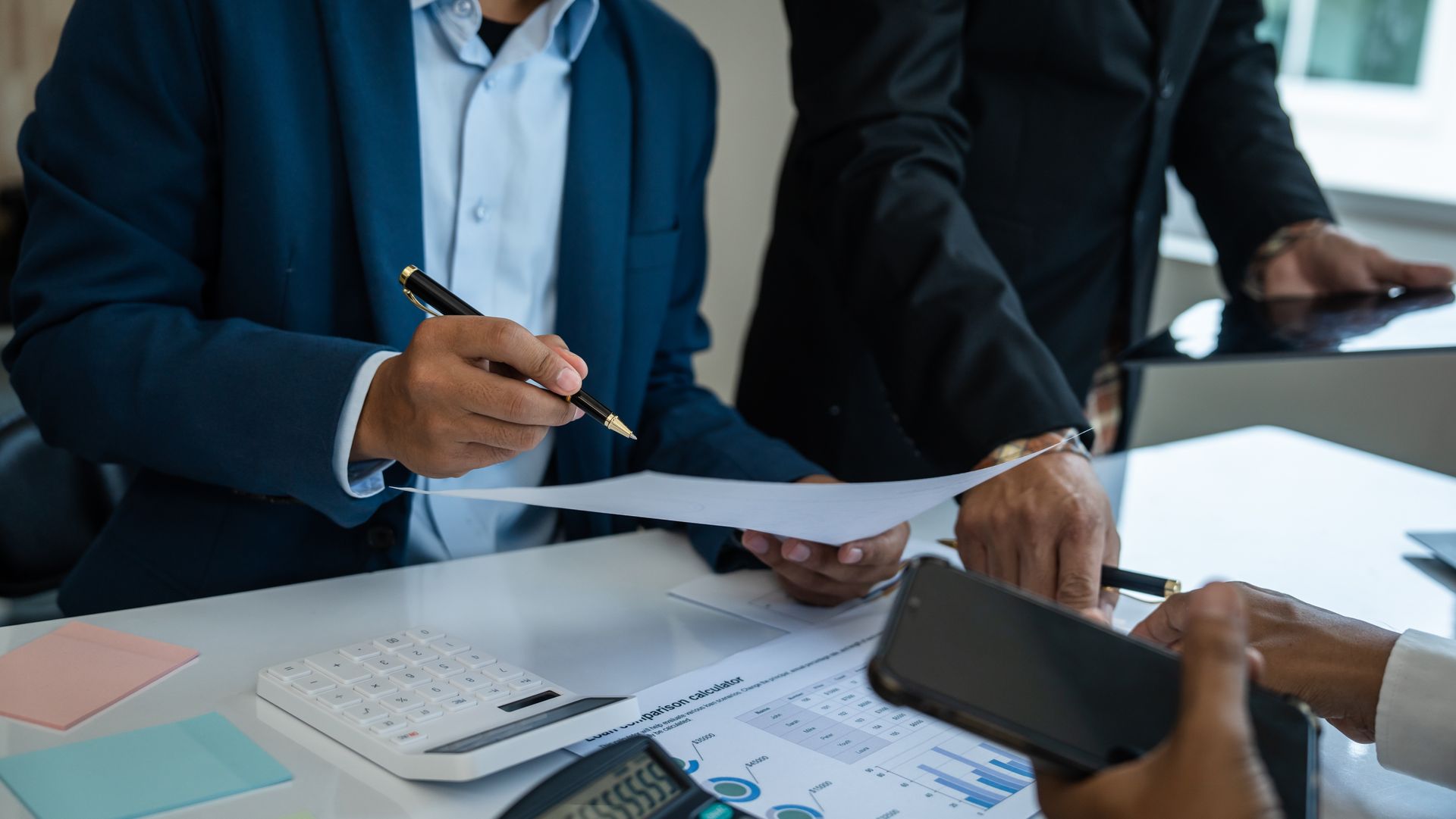 A group of business people are sitting at a table looking at a piece of paper.
