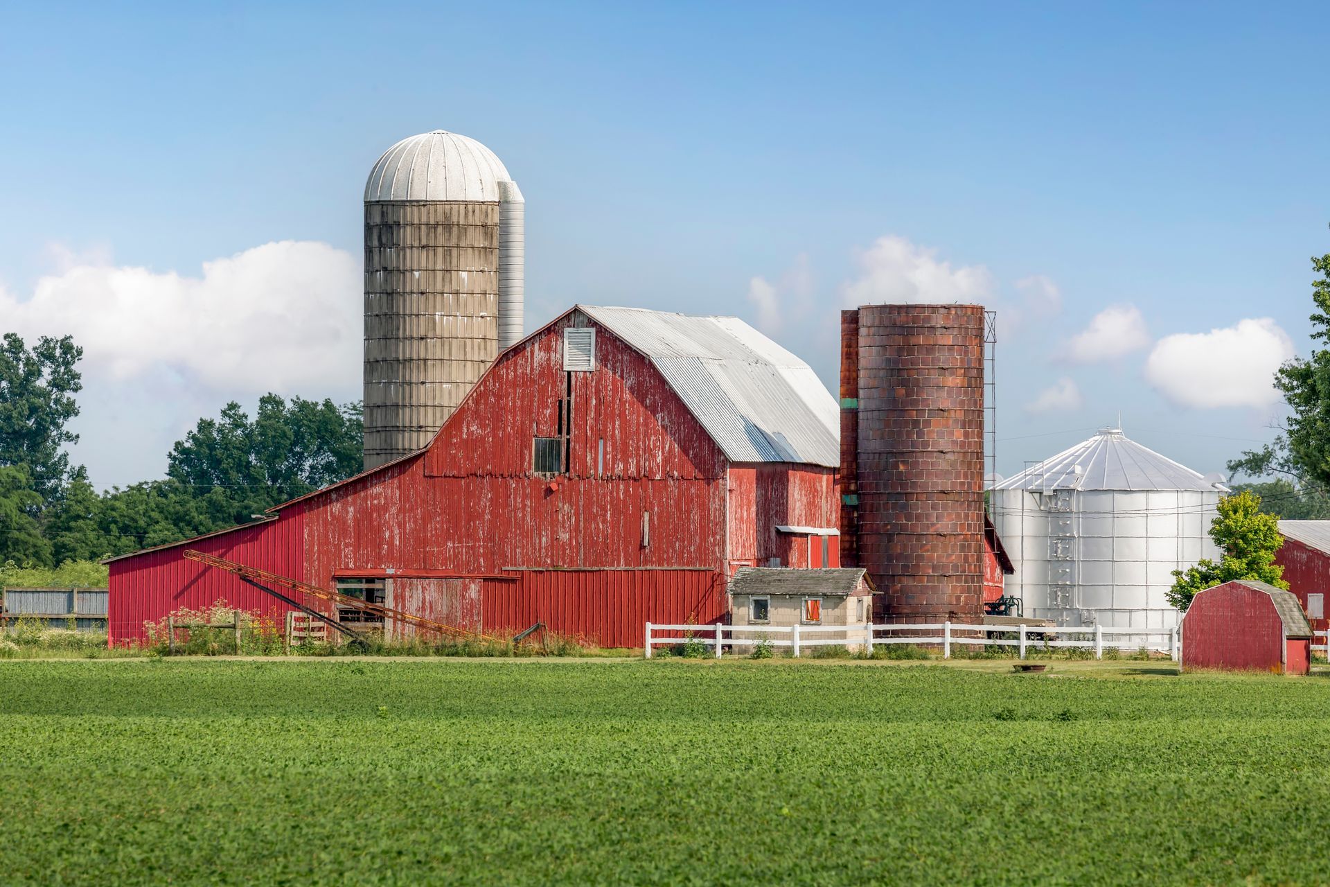A red barn is sitting in the middle of a grassy field.