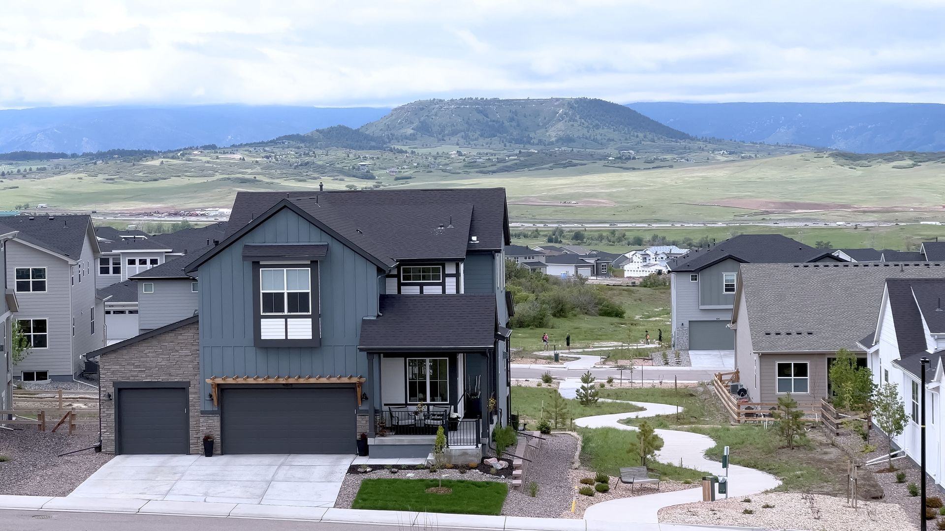 Houses in a residential neighborhood with a mountain in the background. Blue and gray siding.