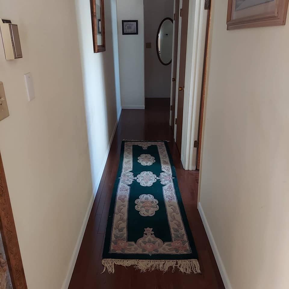 A hallway with a rug and a mirror on the wall