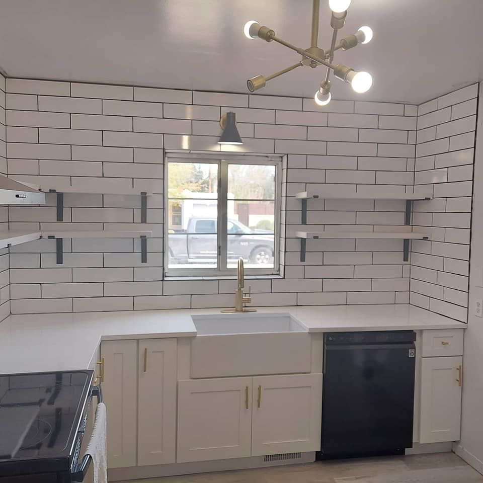 A kitchen with white cabinets a sink and a window