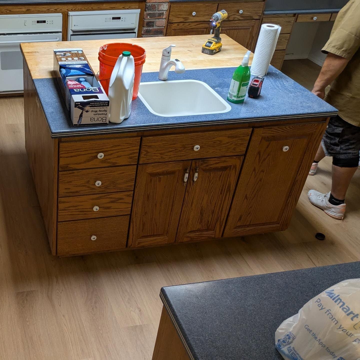 A kitchen island with a sink and a bucket of bleach