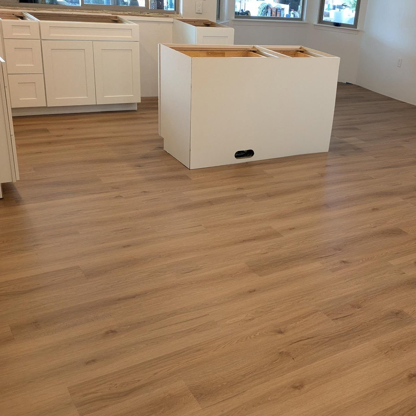 A kitchen with a wooden floor and white cabinets.