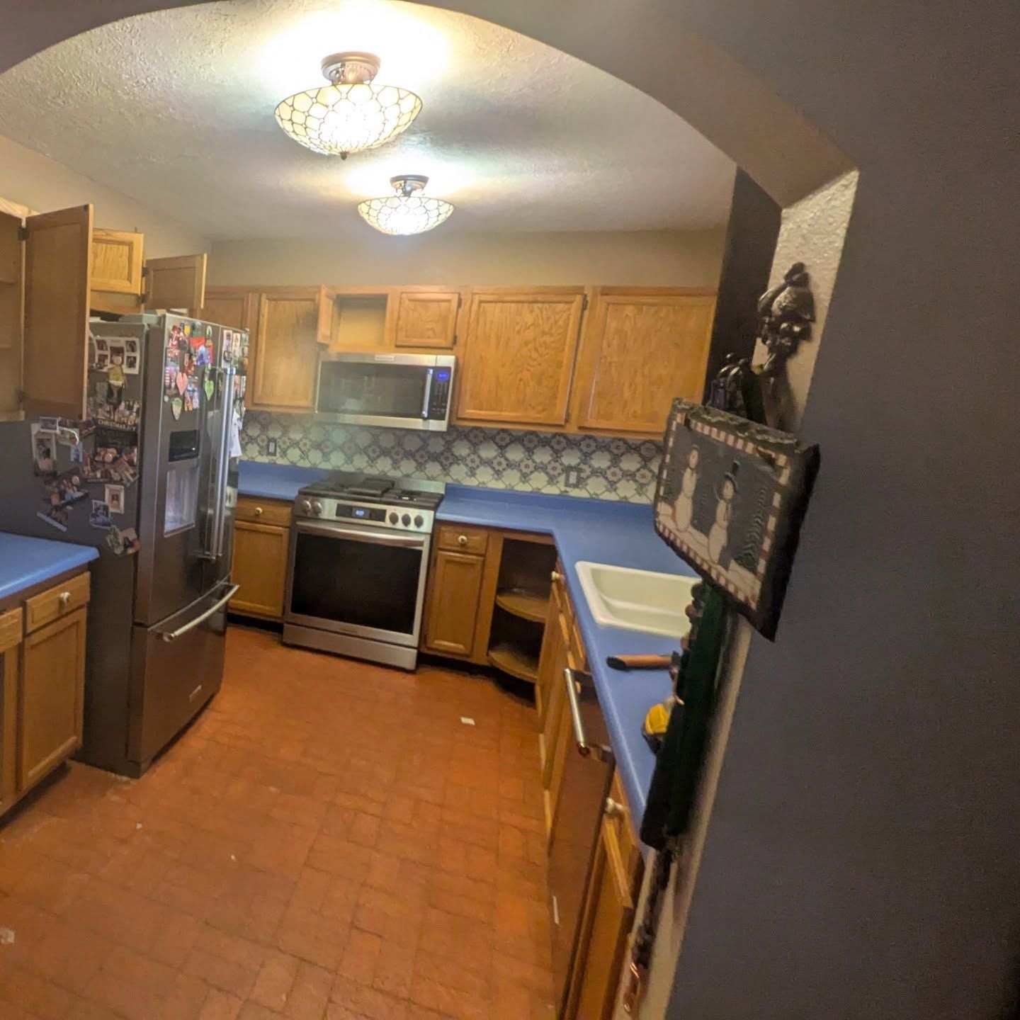 A kitchen with a stove , refrigerator , microwave and sink