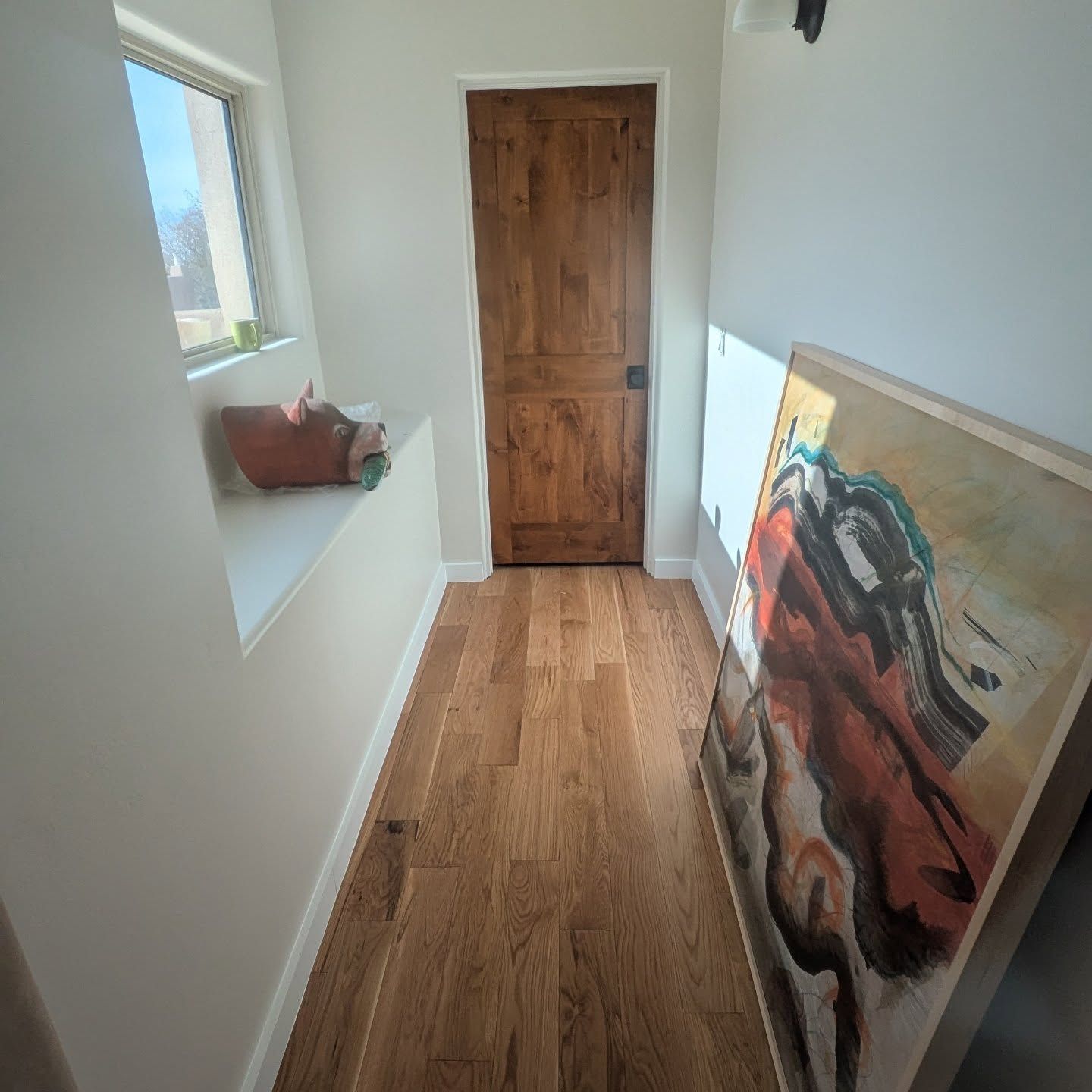 A hallway with hardwood floors and a painting on the wall