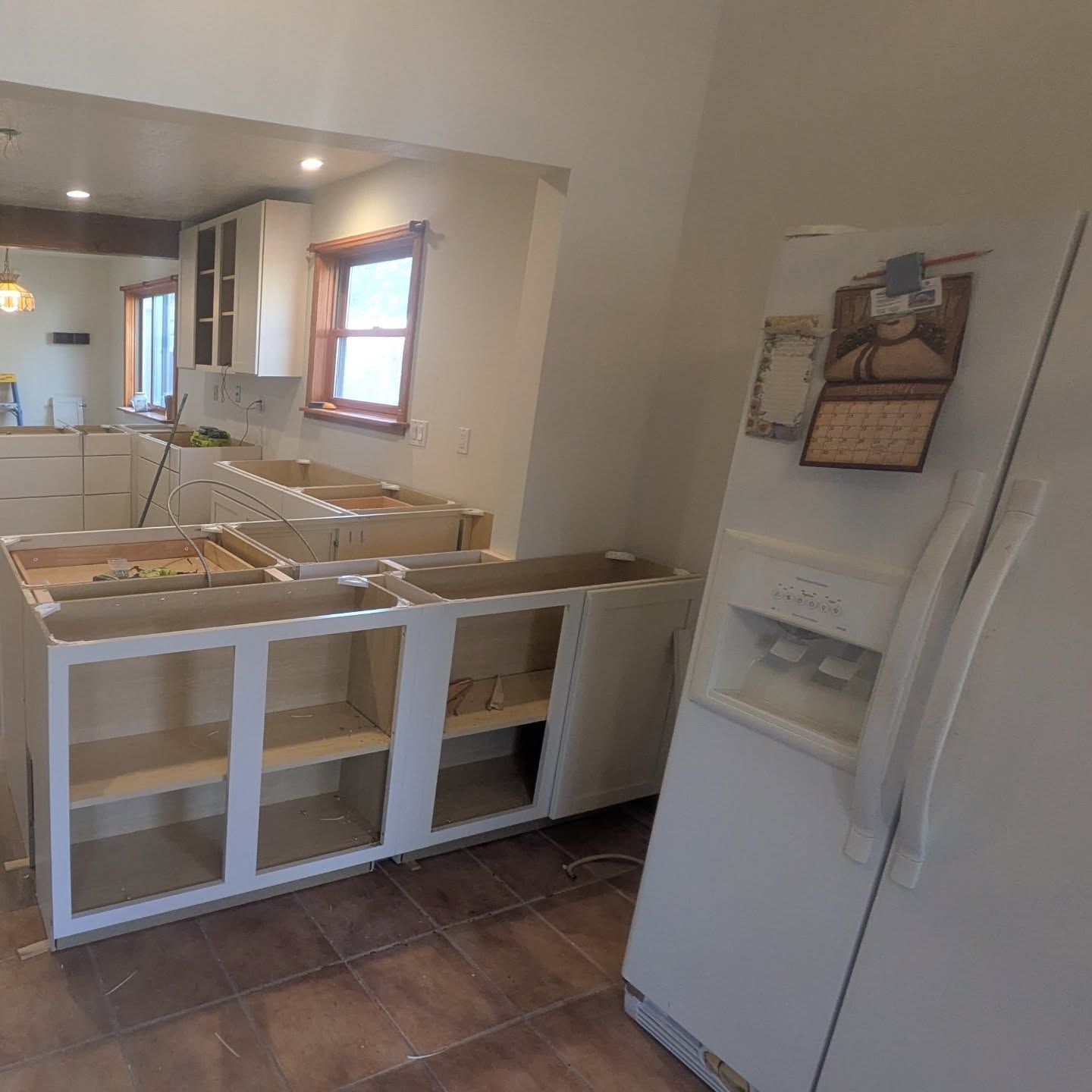 A kitchen with a refrigerator and a calendar on the wall.