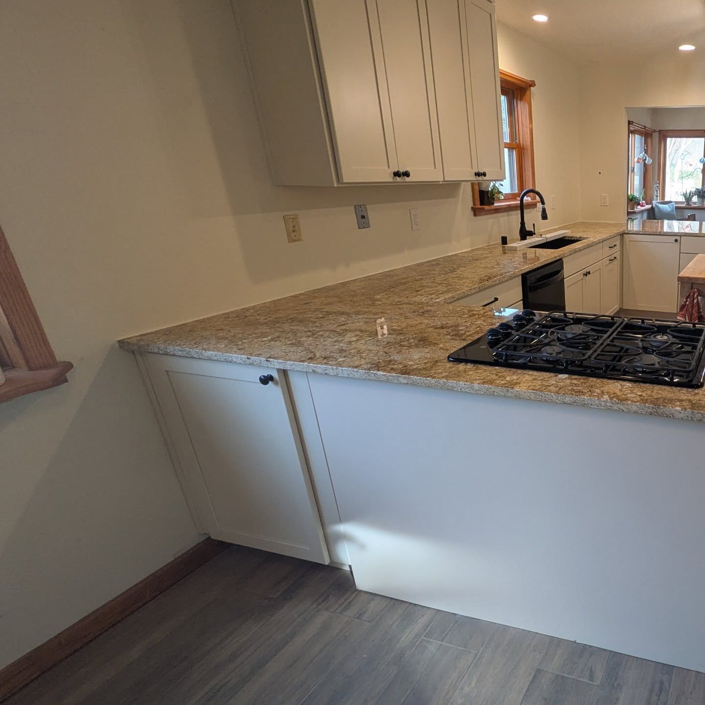 A kitchen with granite counter tops , white cabinets and a stove top oven.