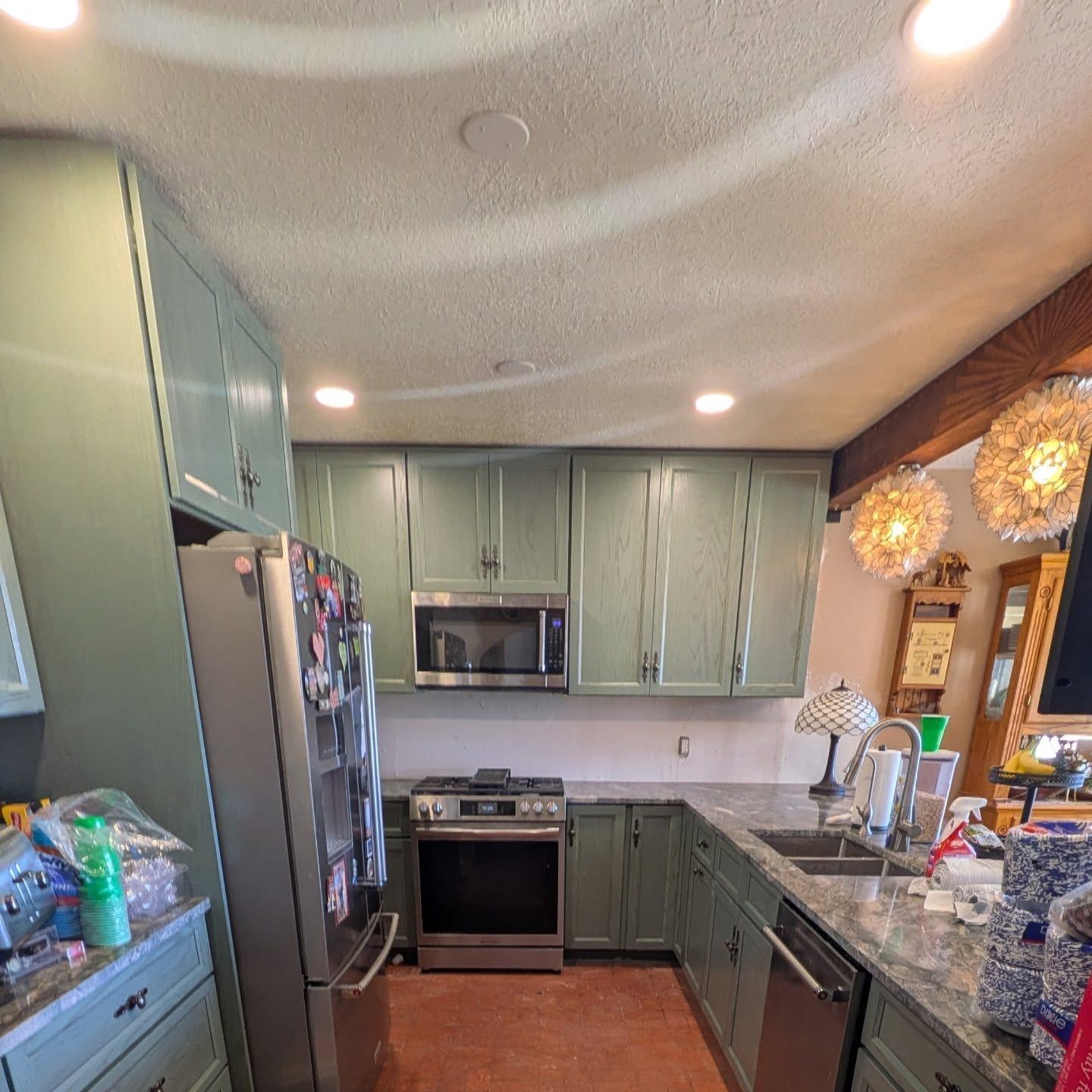 A kitchen with green cabinets and stainless steel appliances