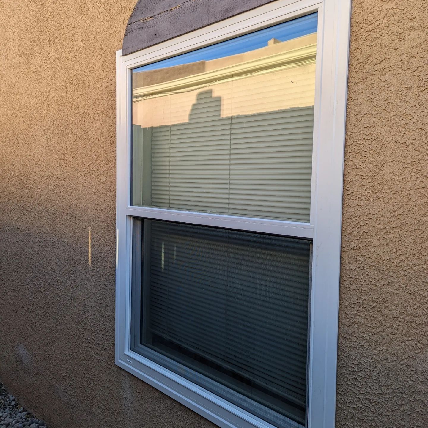 A window with blinds is on the side of a building