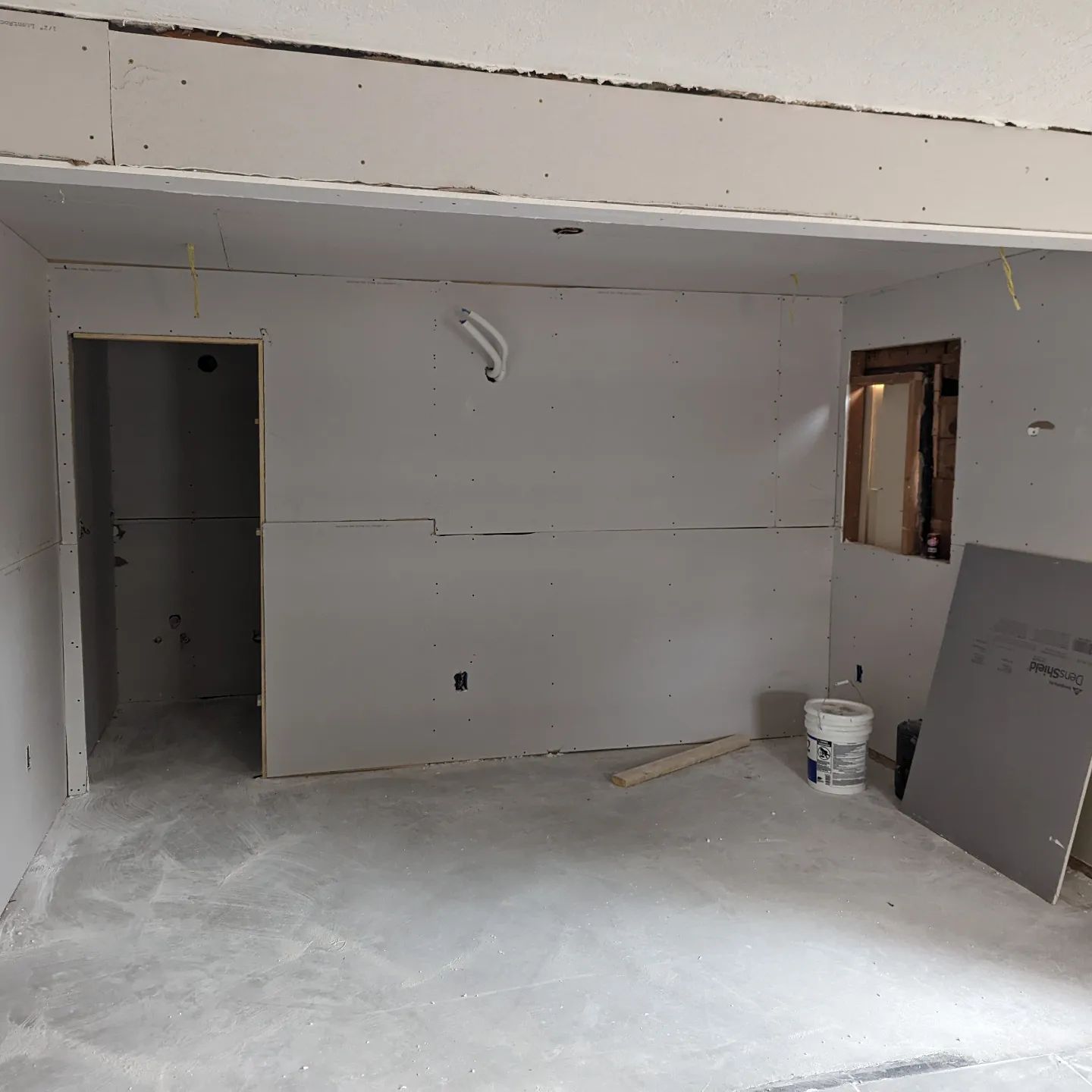 An empty room with a bucket of paint on the floor