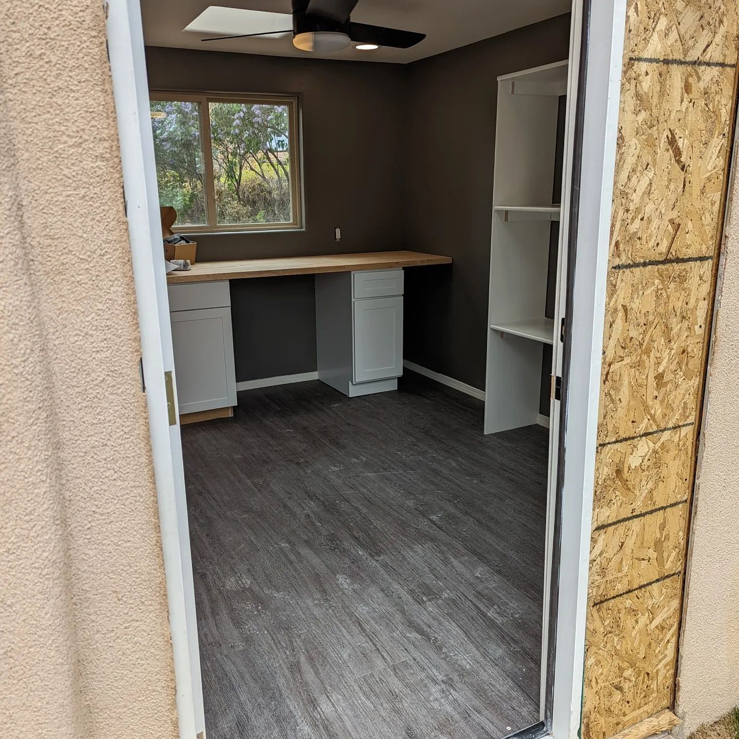 A room with a desk and a ceiling fan