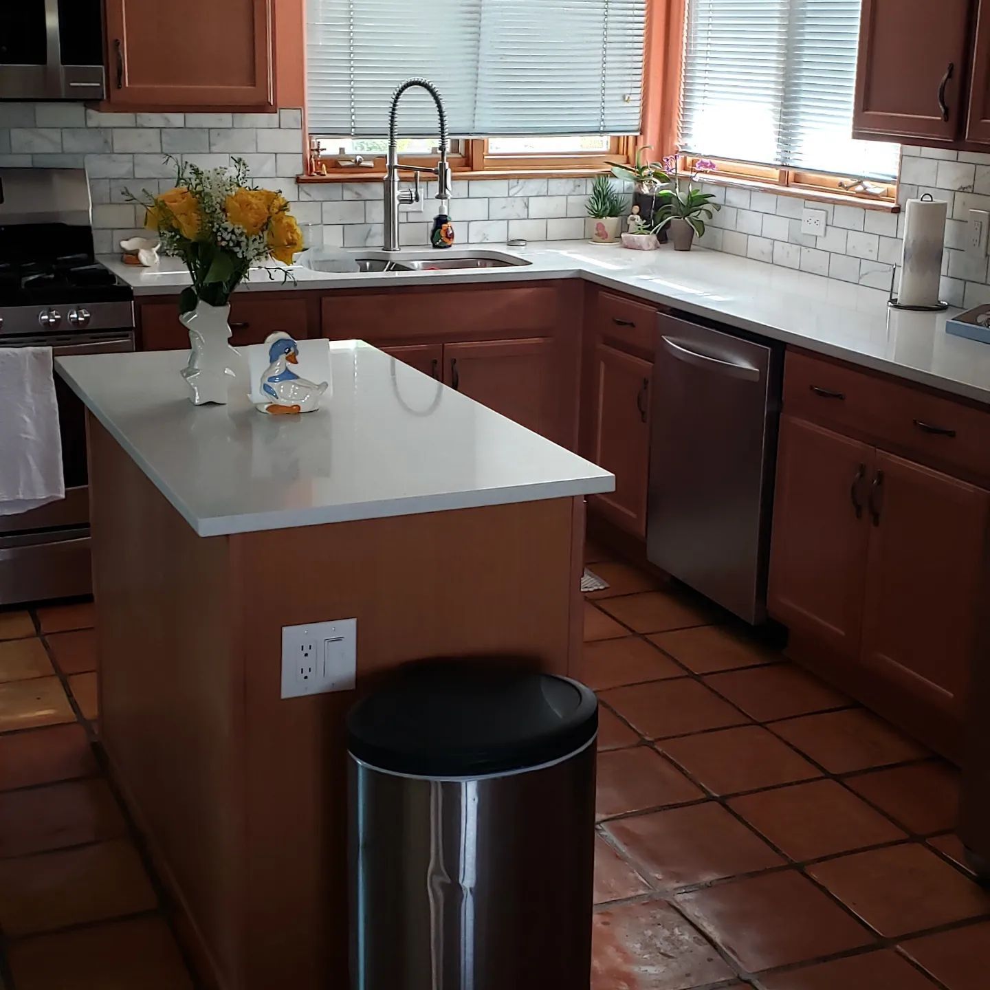 A kitchen with a large island and a stainless steel trash can