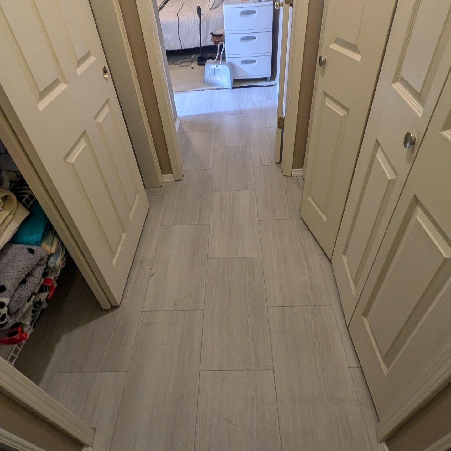 A hallway with white doors leading to a bedroom