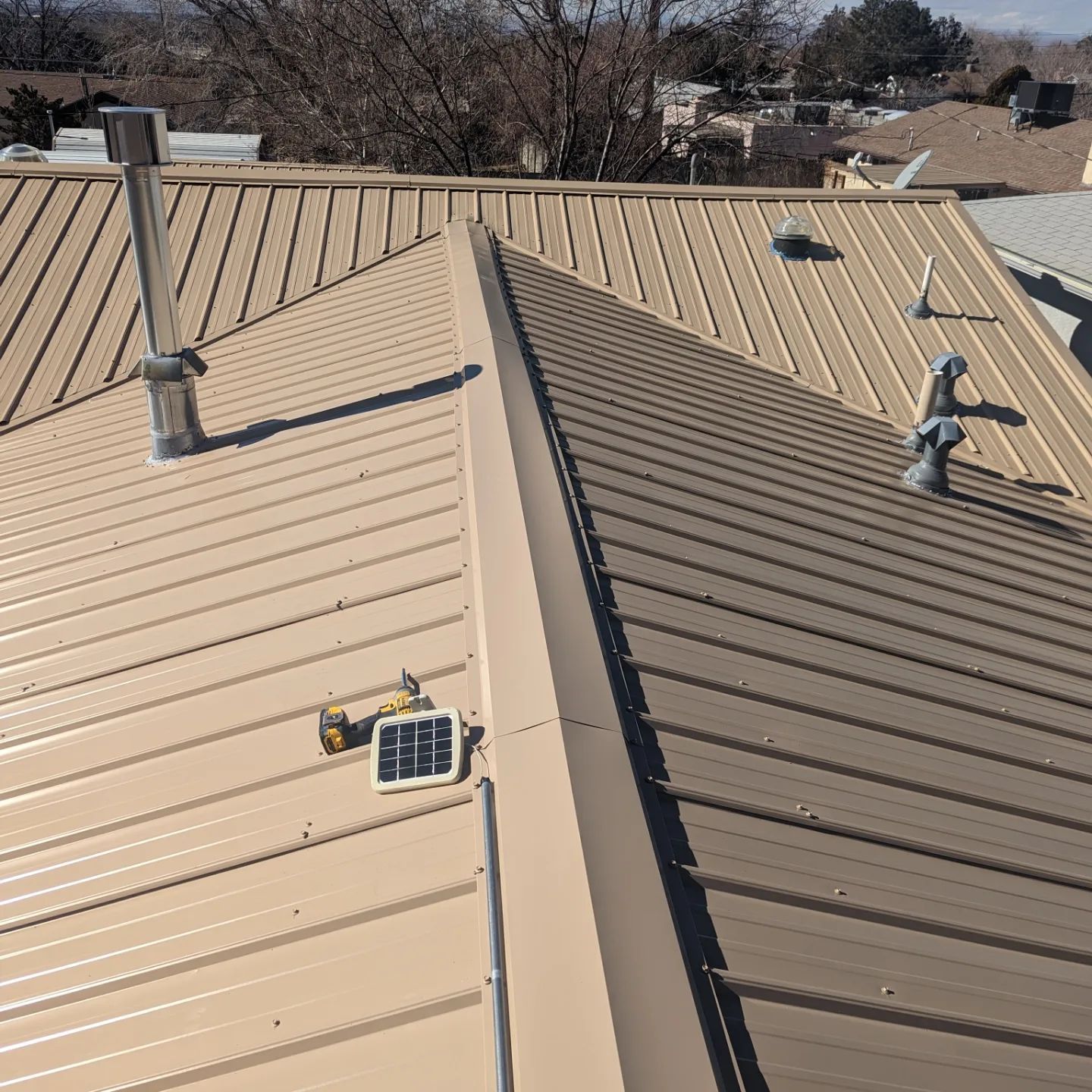 A tan metal roof with a solar panel on it