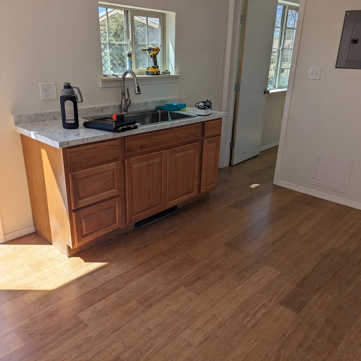 A kitchen with a sink , cabinets , and hardwood floors.