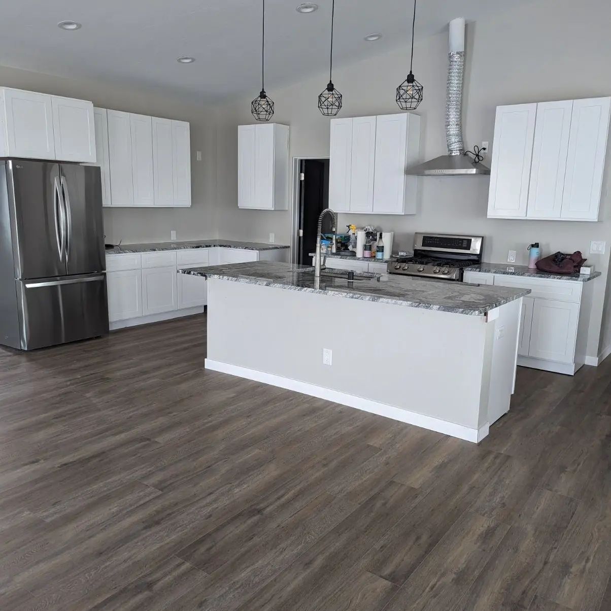 A kitchen with white cabinets , stainless steel appliances , and a large island.