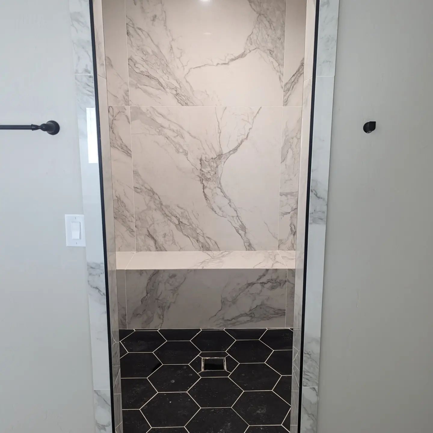 A bathroom with marble walls and a black tile floor.