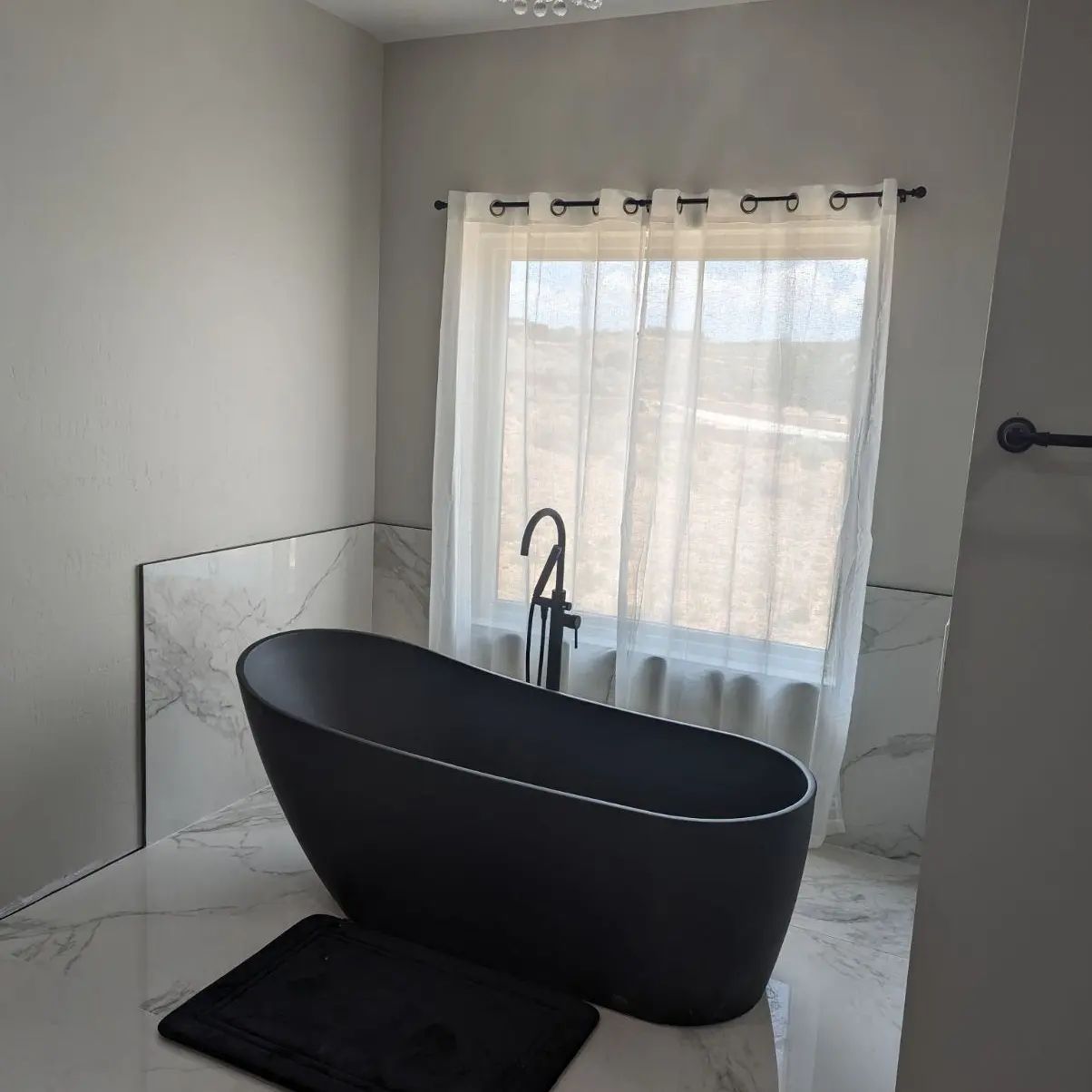 A black bathtub in a bathroom next to a window