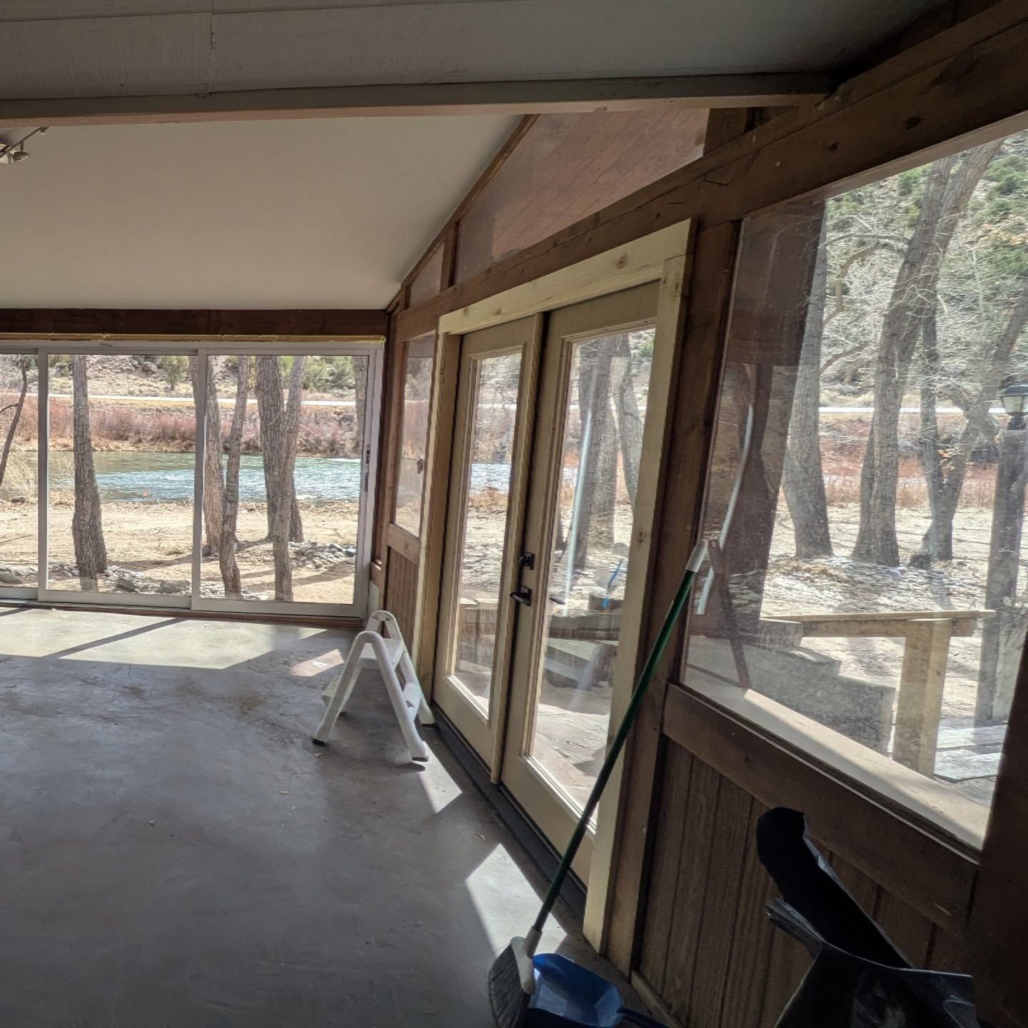 A screened in porch with a chair and a broom.