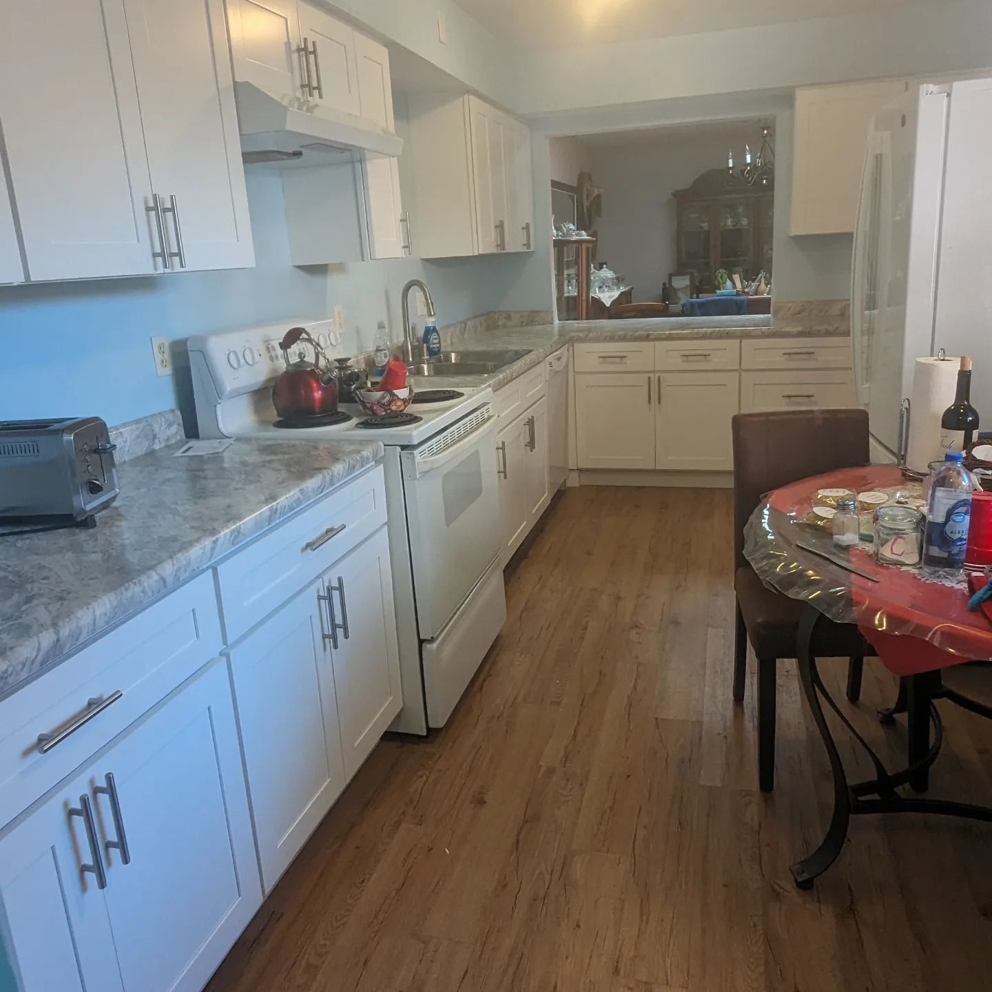 A kitchen with white cabinets and hardwood floors