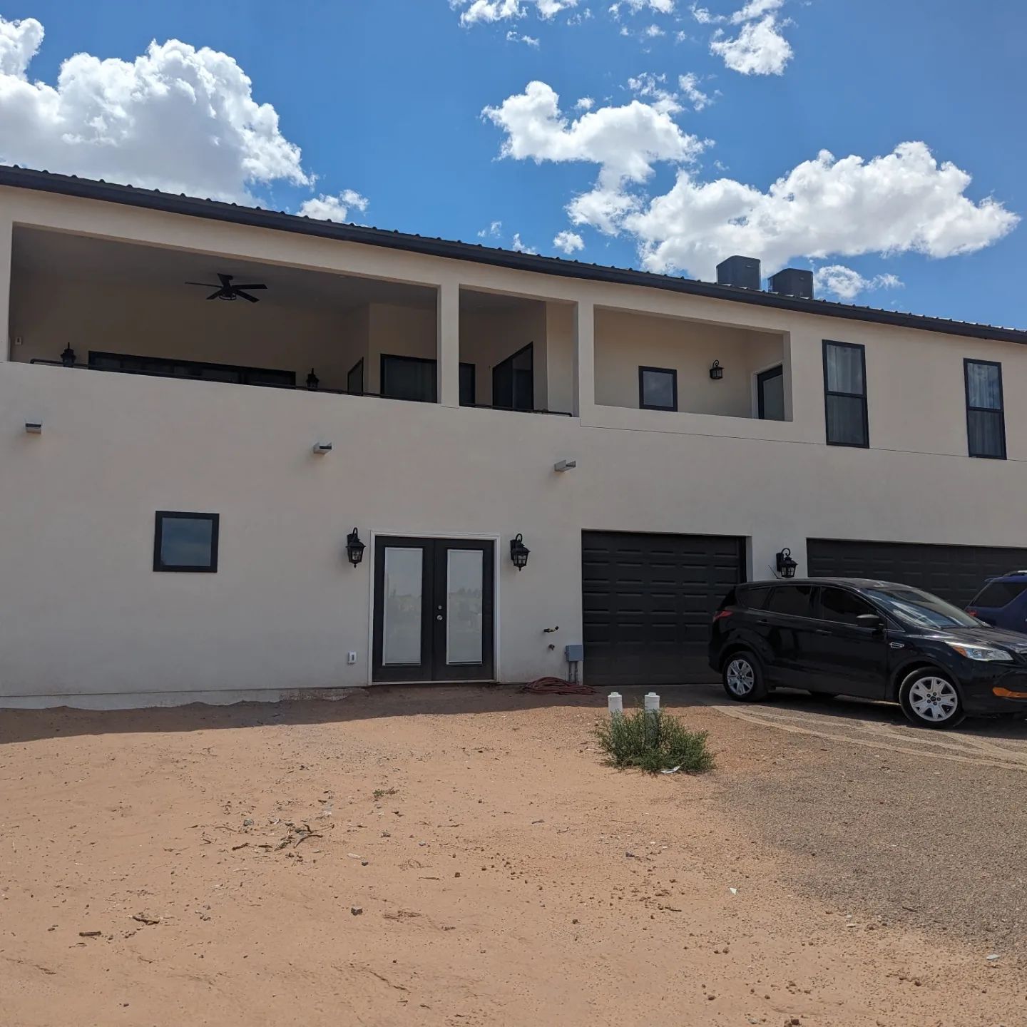 A white house with a black car parked in front of it
