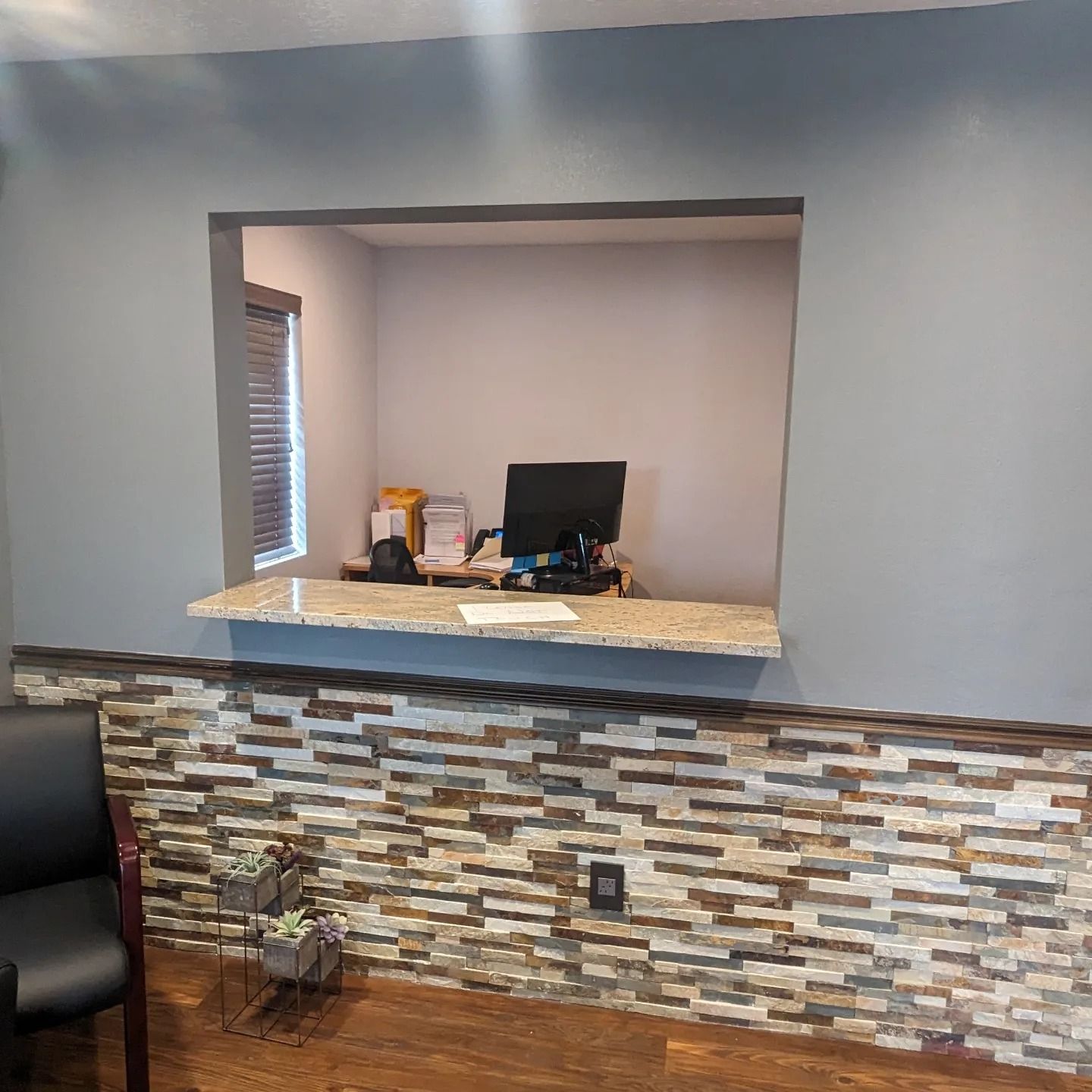 A waiting room with a brick wall and a desk with a computer on it.