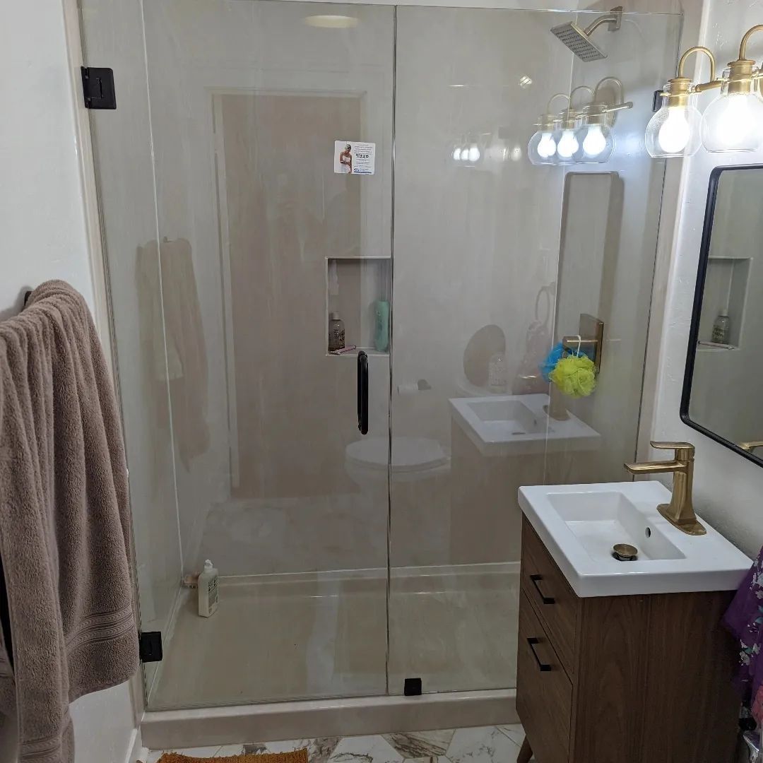 A bathroom with a glass shower door , sink , mirror and toilet.