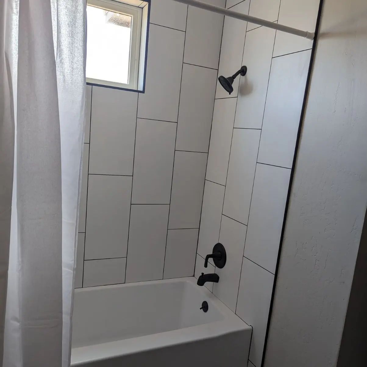A bathroom with white tiles and a bathtub
