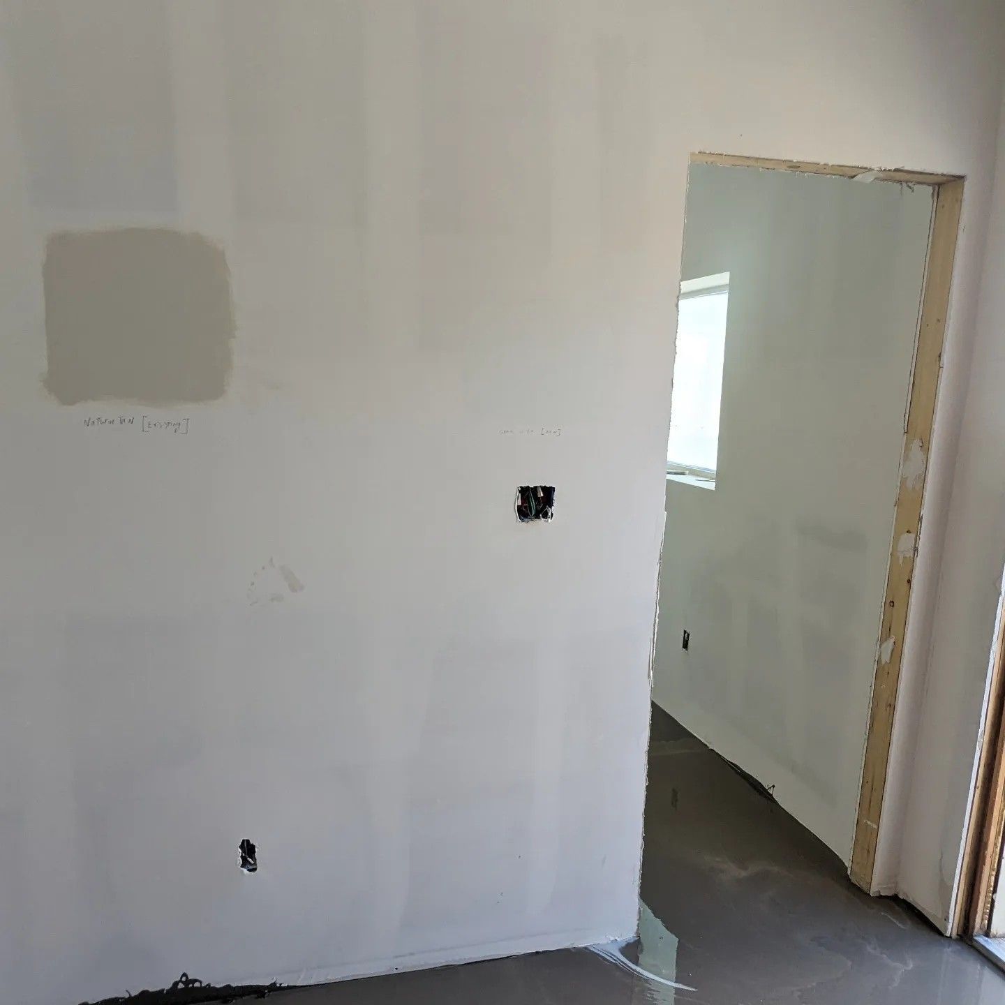 A room with a white wall and a doorway leading to another room.