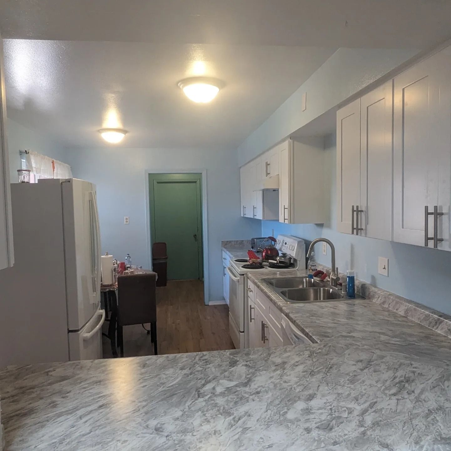 A kitchen with marble counter tops and white cabinets