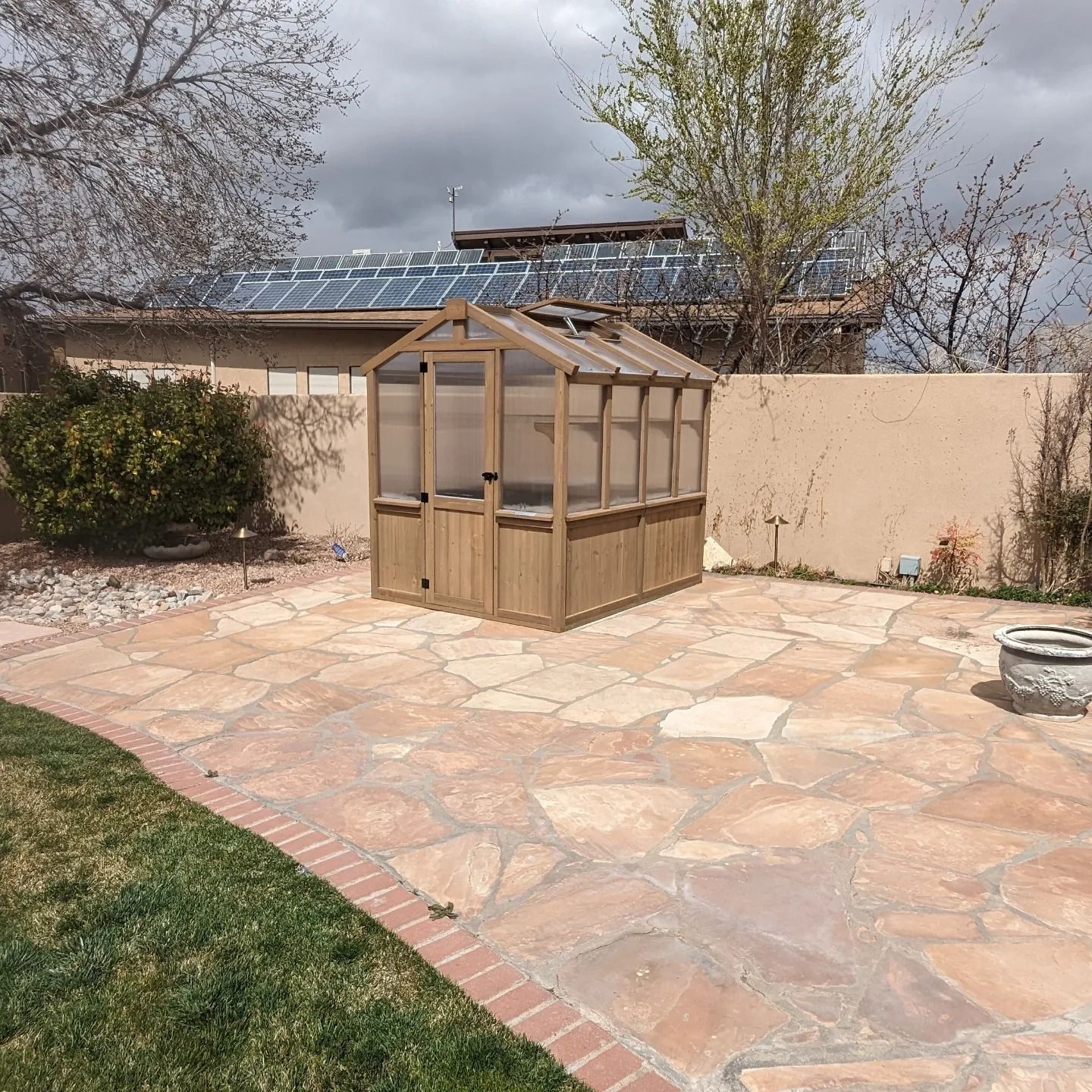 A small greenhouse is sitting on a stone patio