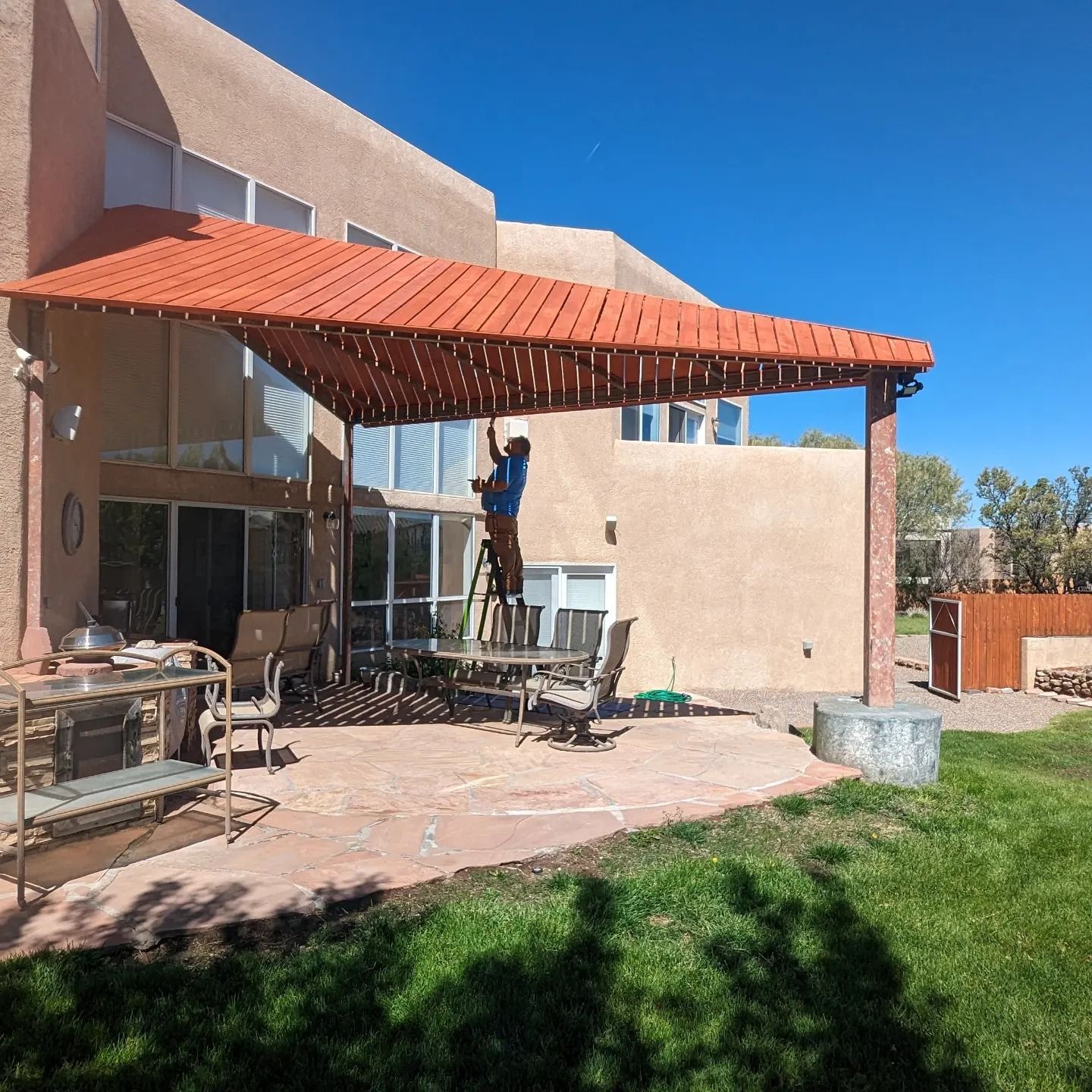A man is standing on a ladder under a red roof
