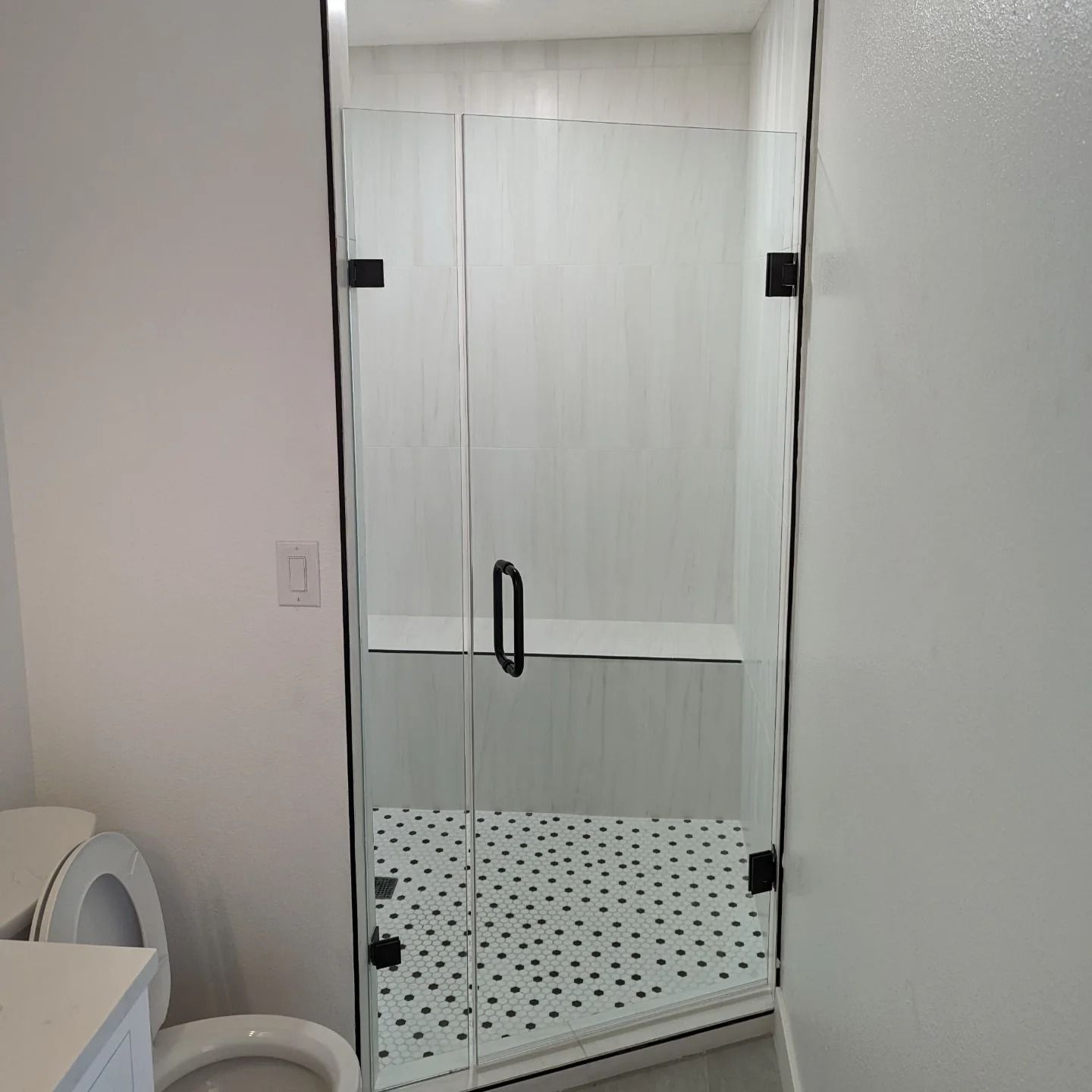 A bathroom with a toilet and a shower with a glass door.