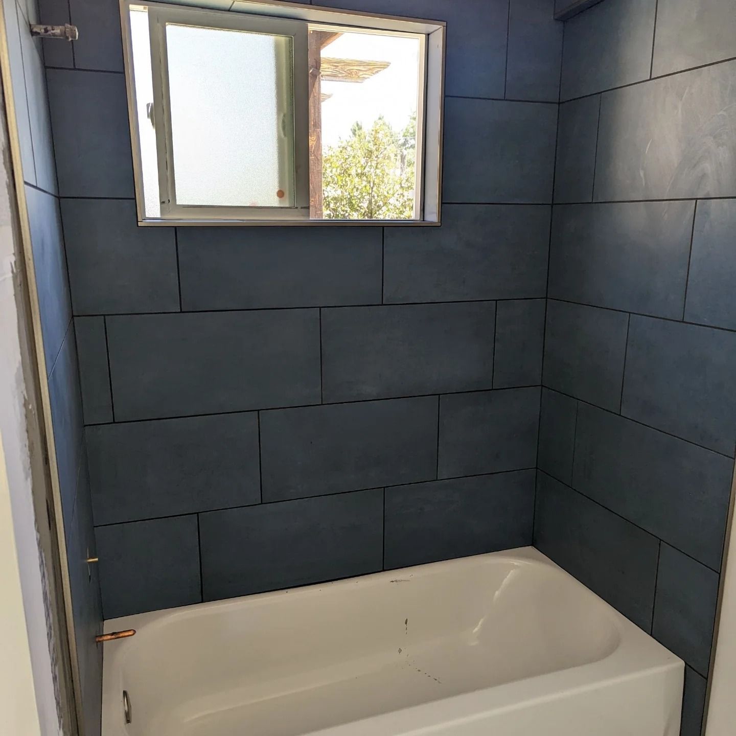 A bathroom with a bathtub and a mirror above it