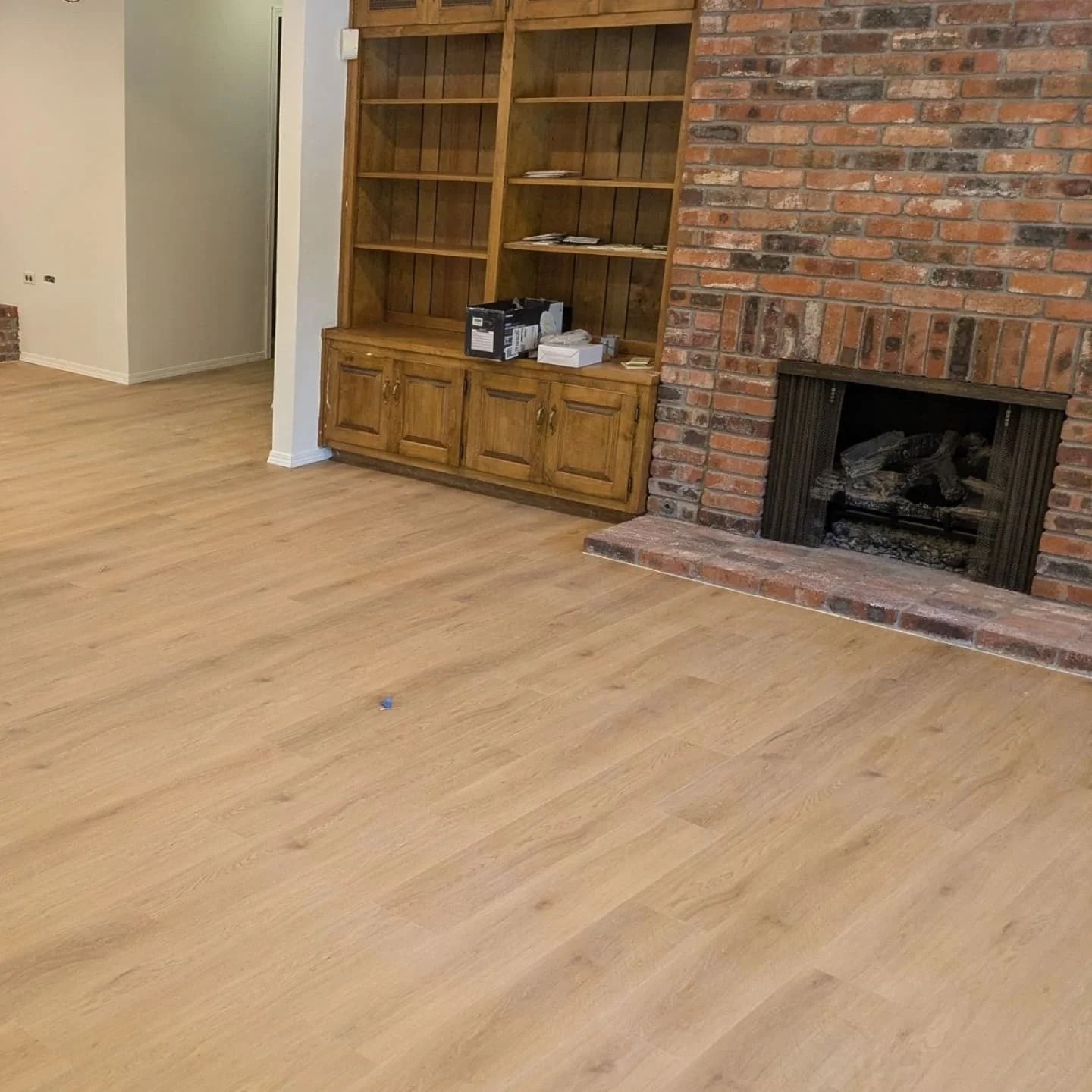 A living room with hardwood floors and a brick fireplace.