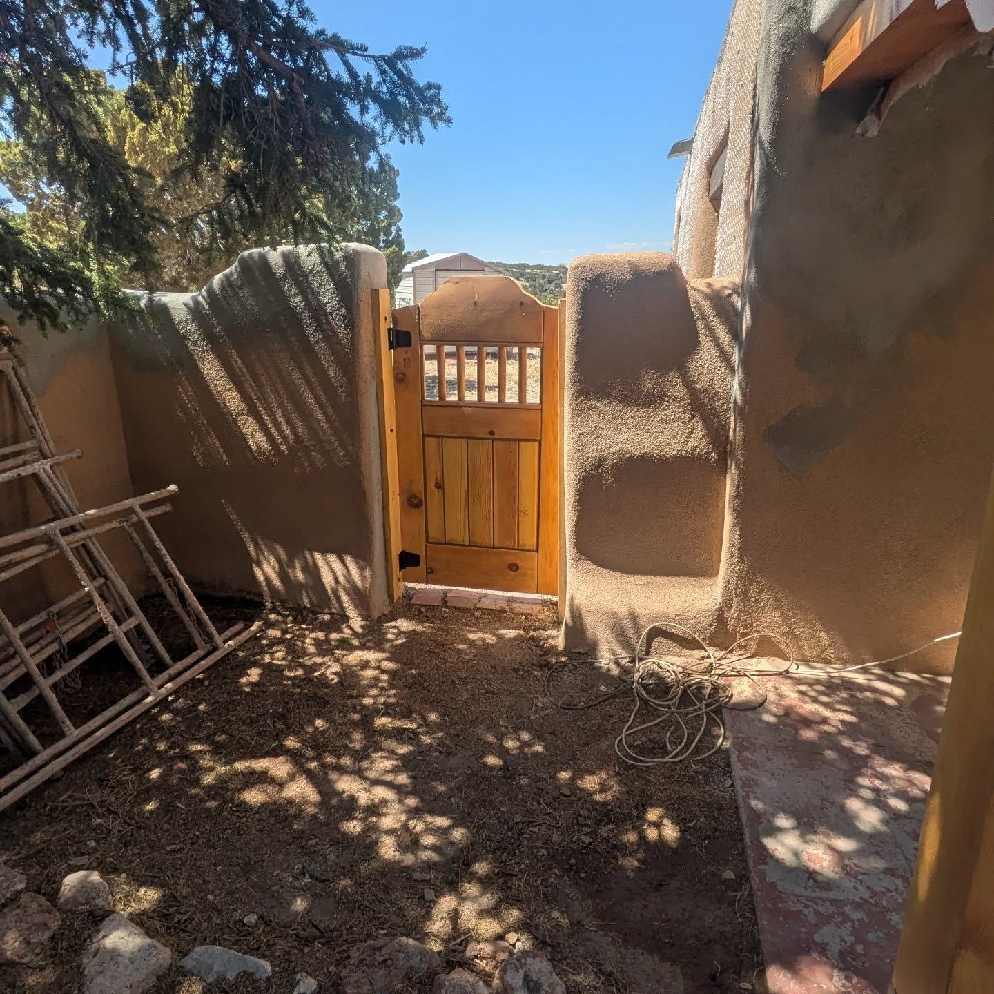 A wooden gate is open to a dirt area