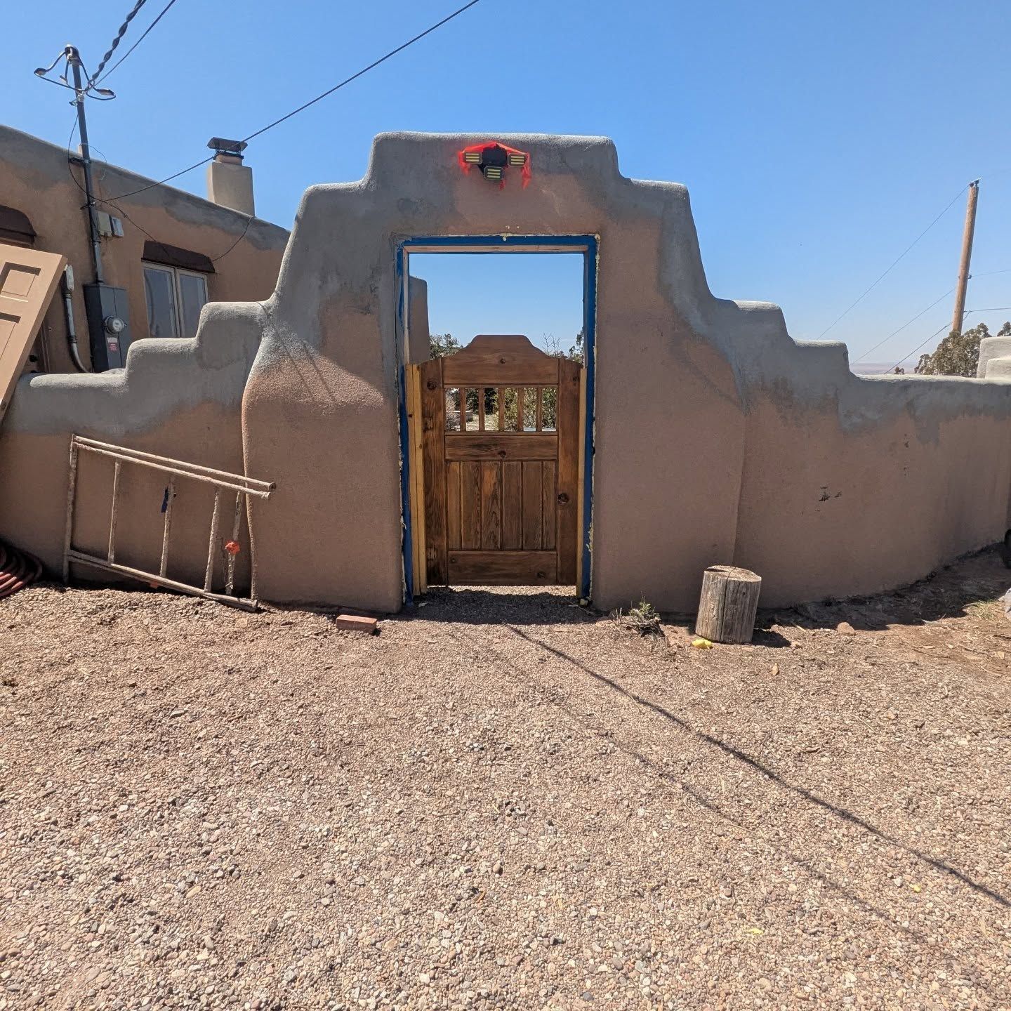 A stone wall with a wooden gate and a ladder in front of it
