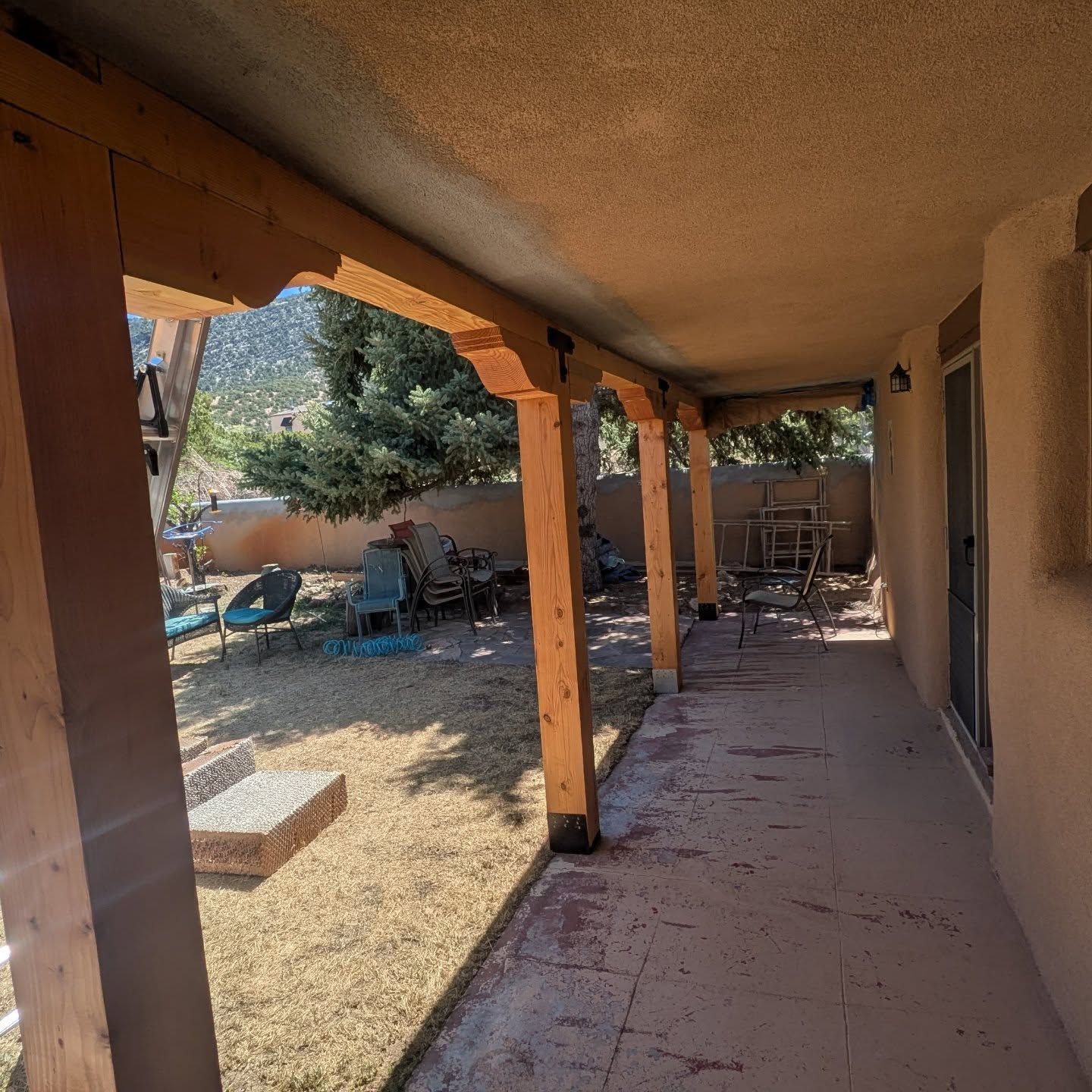 A patio with a sliding glass door leading to a backyard