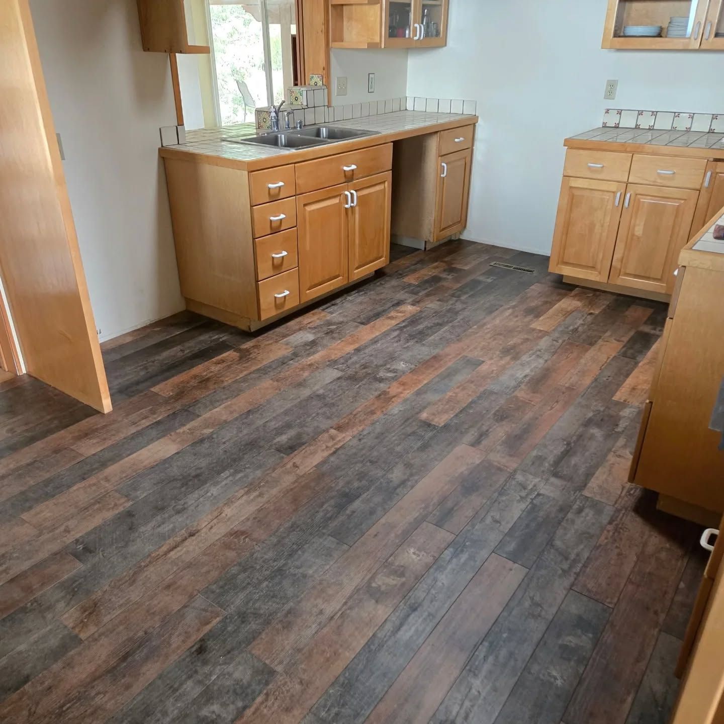 A kitchen with wooden cabinets , a sink , and a wooden floor.