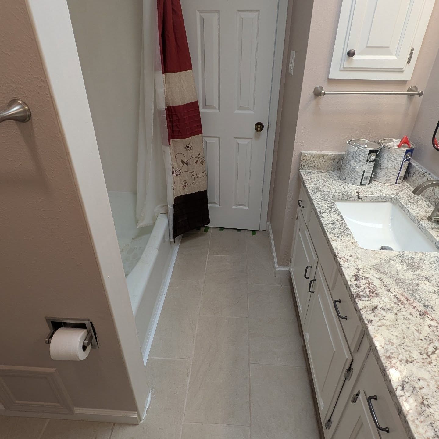 A bathroom with a sink a shower and a toilet paper dispenser