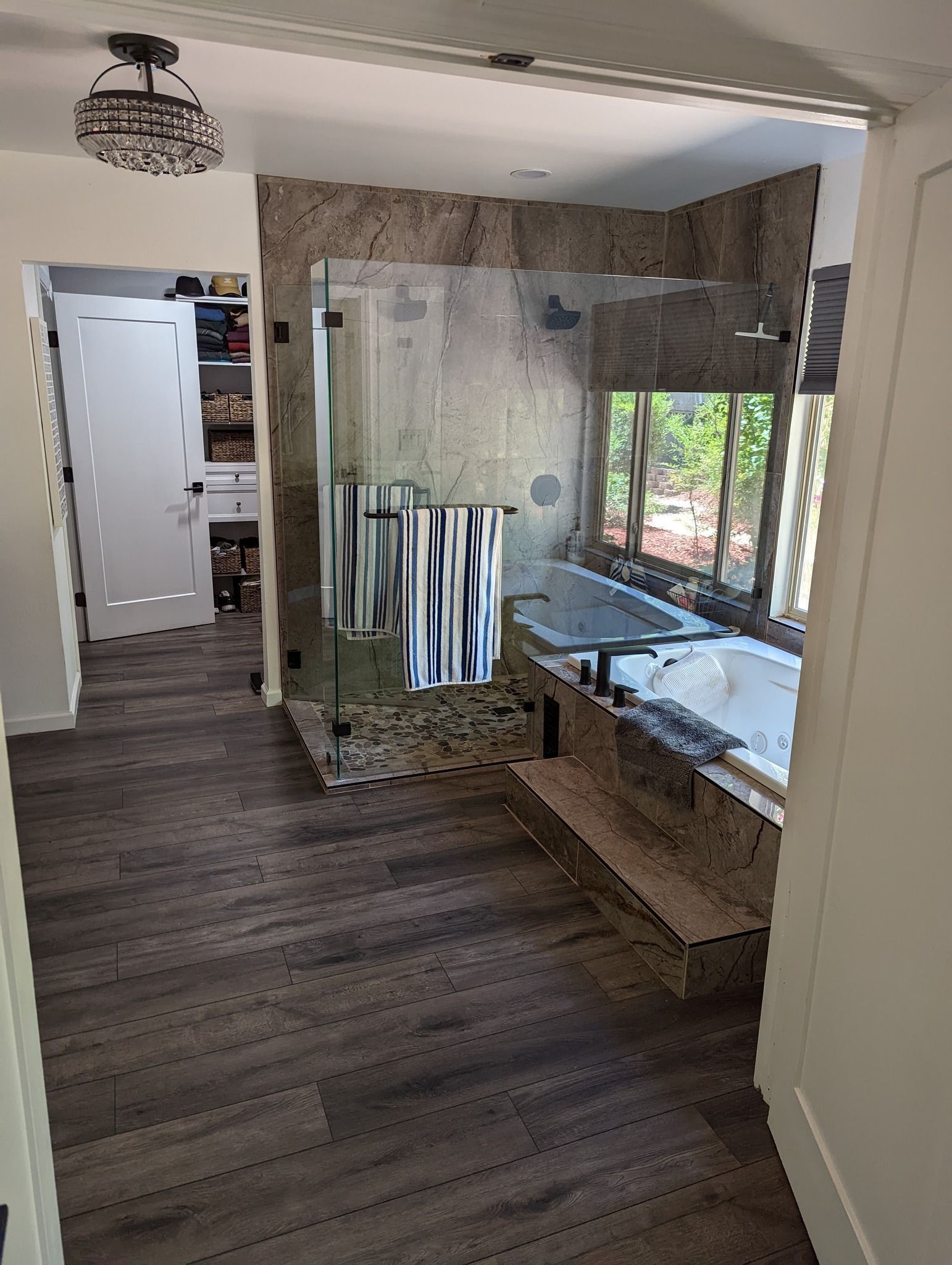 A bathroom with a walk in shower , tub , and window.