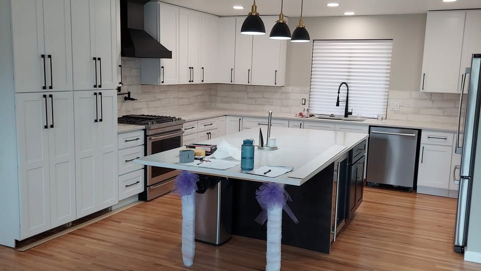 A kitchen with white cabinets , stainless steel appliances , and a large island.