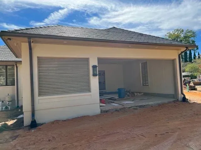 A white house with a garage underneath it is being built.